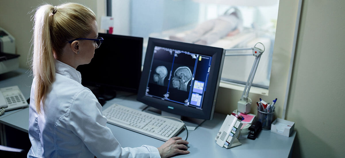 female radiologist examining MRI using keyboard and mouse